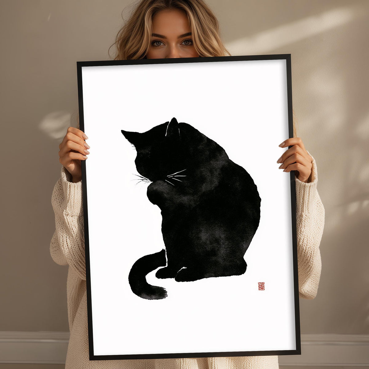 A woman holding a framed black cat illustration.