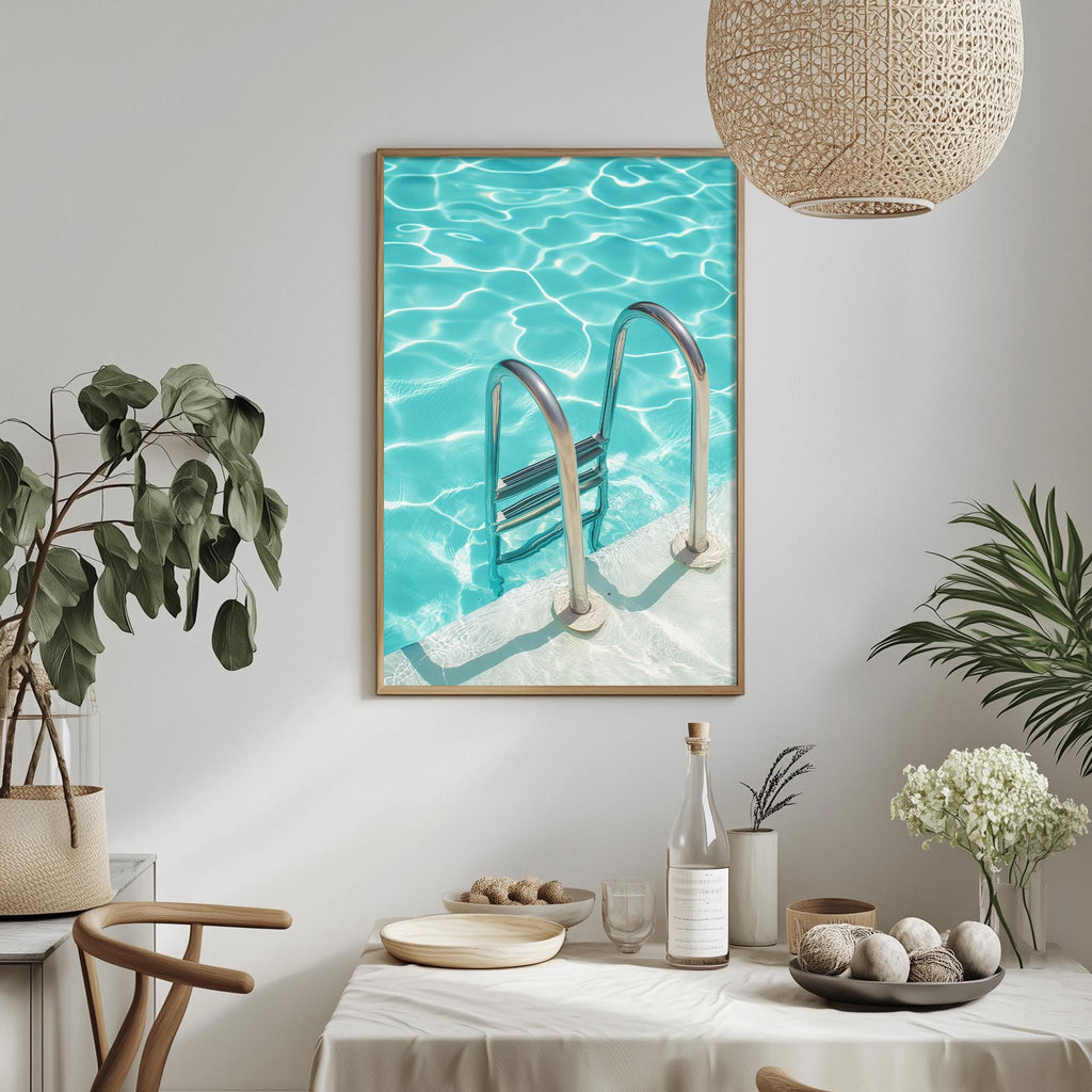 a framed photograph of a swimming pool with a ladder, hanging on a wall above a dining table with various decorative items and plants.