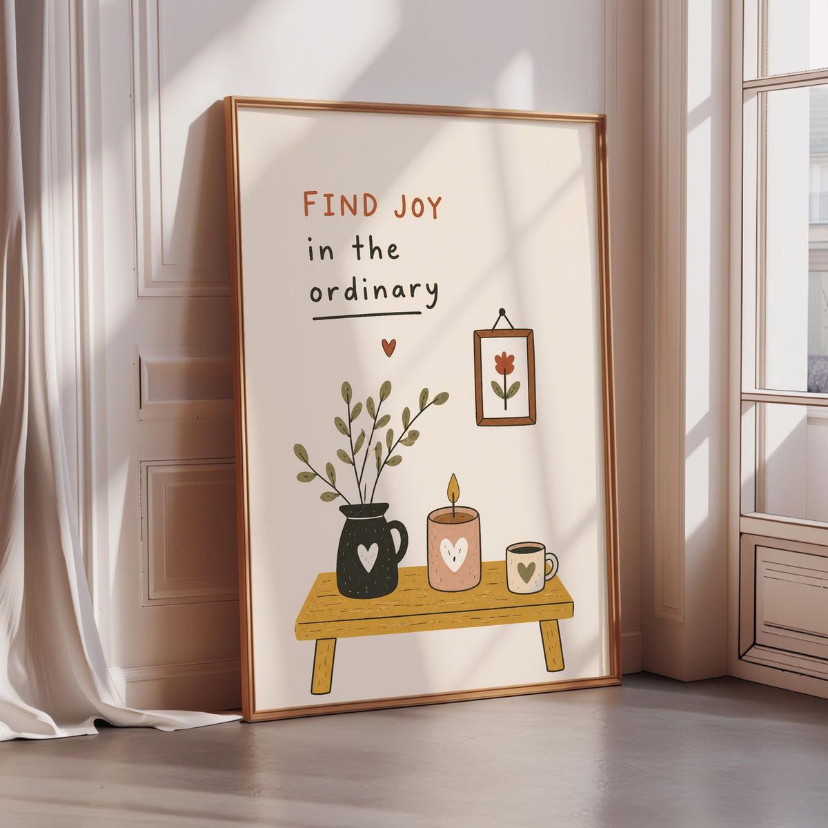 a framed poster with a simple illustration of a table with a vase of flowers, a candle, and a cup, accompanied by the text "Find joy in the ordinary" and a heart symbol.