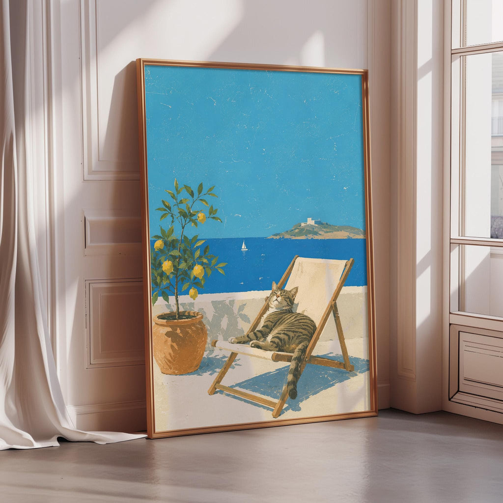 A framed painting depicting a cat lounging in a beach chair, with a potted plant and a sailboat visible in the background, set against a bright blue sky and ocean.