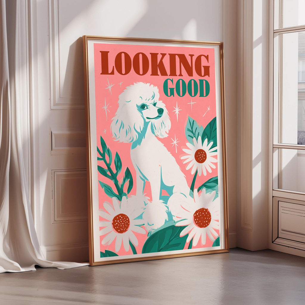 A framed poster with a white poodle and flowers on a pink background, with the text "Looking Good" written on it.