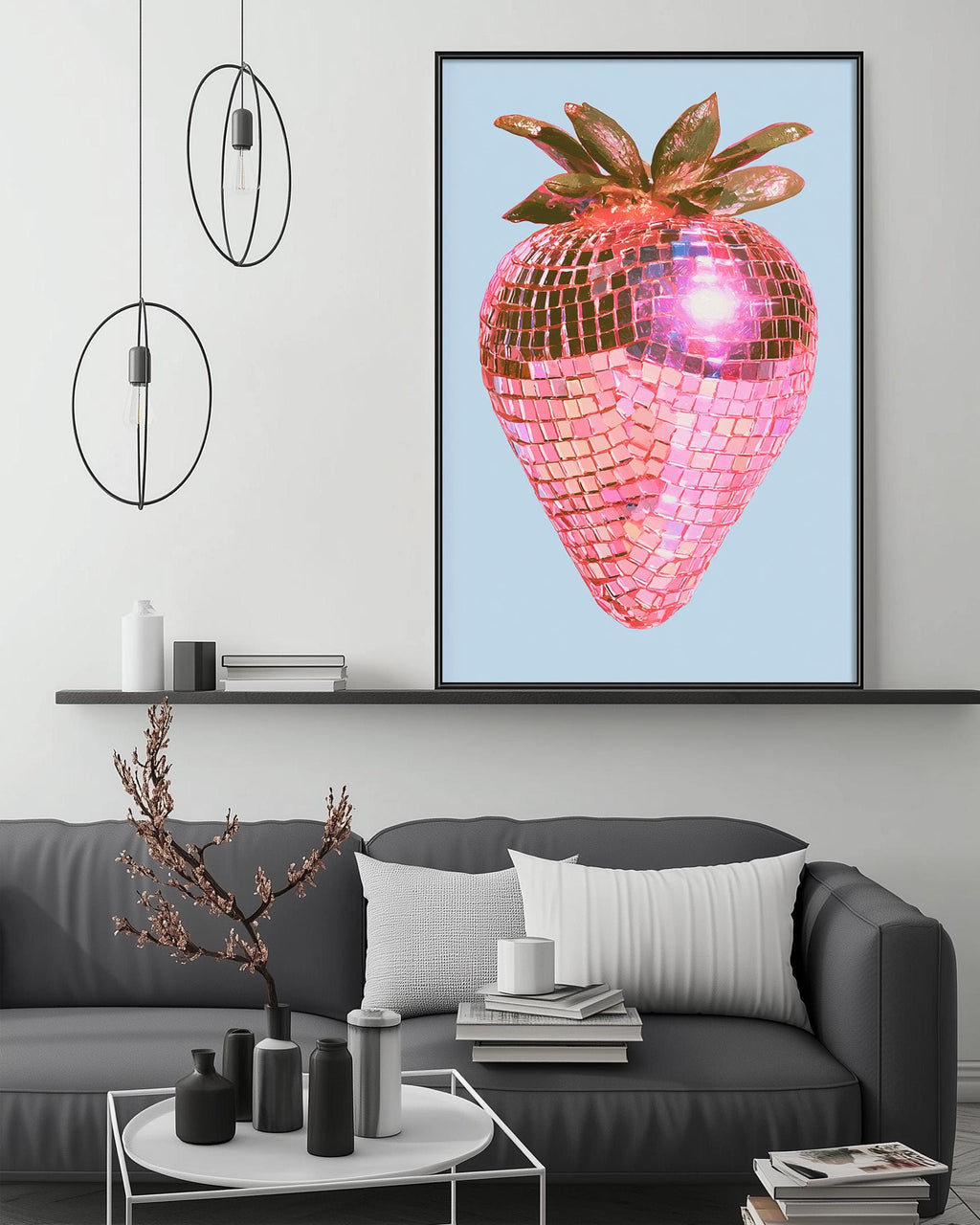 a modern living room with a gray sofa, a coffee table, and a large framed artwork of a pink disco ball with a strawberry design hanging on the wall above the sofa.