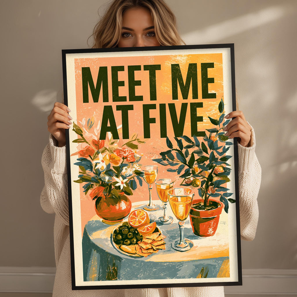 A woman holding a framed poster with a colorful illustration of a table with food and drinks, including wine glasses, oranges, and a vase of flowers.
