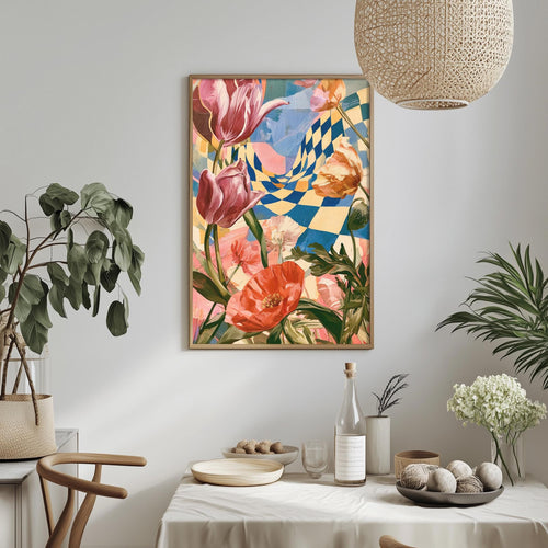 a dining table with a white tablecloth, a vase of white flowers, a bottle, and a bowl of fruit. Above the table, there is a framed painting of colorful flowers and a checkered pattern.