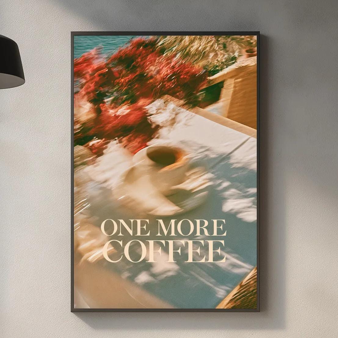 a kitchen counter with various items such as a cutting board, a coffee maker, and a plant. Above the counter, there is a framed poster with the text "ONE MORE COFFEE" displayed on it.