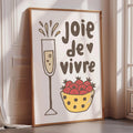 A framed poster with a glass of champagne and a bowl of strawberries, accompanied by the text "Joie de vivre" (French for "joy of life")