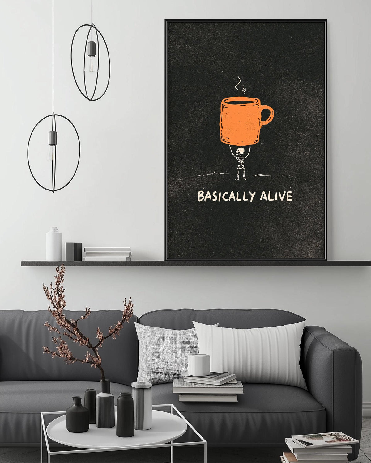 a living room with a gray couch, a coffee table, and a large framed poster on the wall. The poster depicts a coffee cup with a skeleton holding it, accompanied by the text "BASICALLY ALIVE".