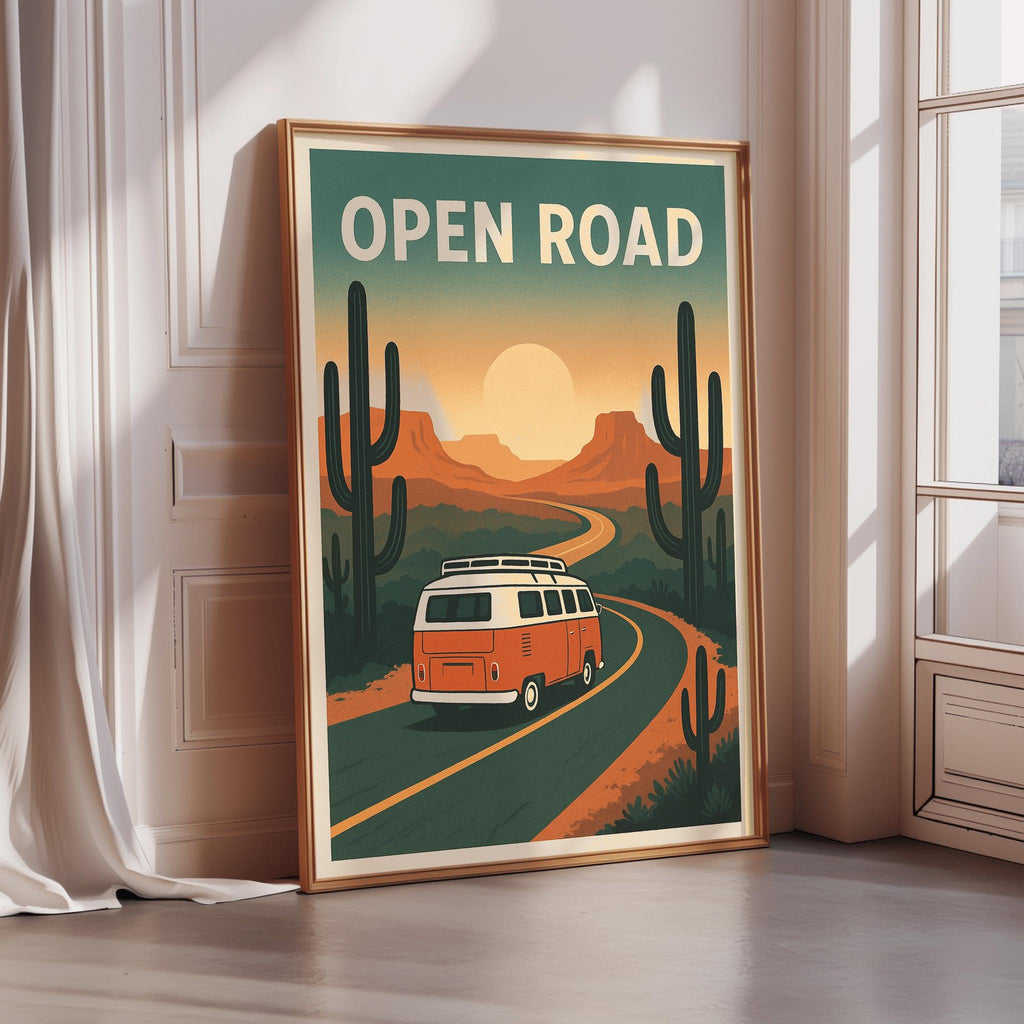 a framed poster with a vintage-style illustration of a van driving down a road surrounded by desert scenery, with cacti and mountains in the background.