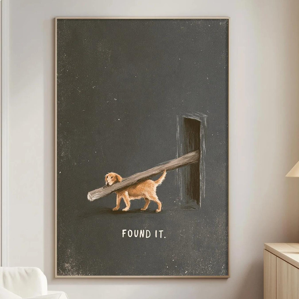 a living room with a large black and white painting hanging on the wall. The painting depicts a dog carrying a large wooden log, with the text "FOUND IT" written below the image.