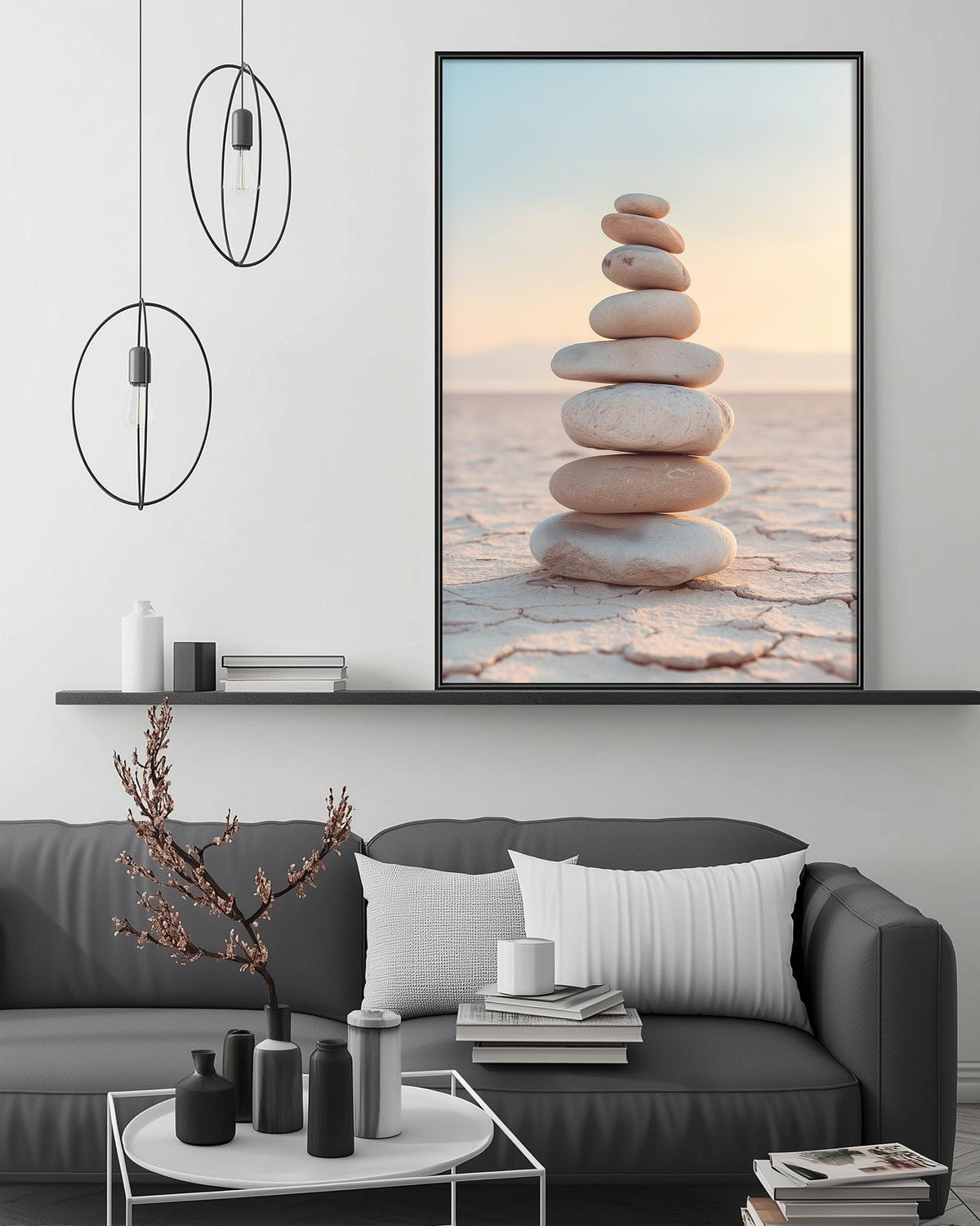 a modern living room with a gray sofa, a coffee table, and a large framed picture of stacked stones on the wall.
