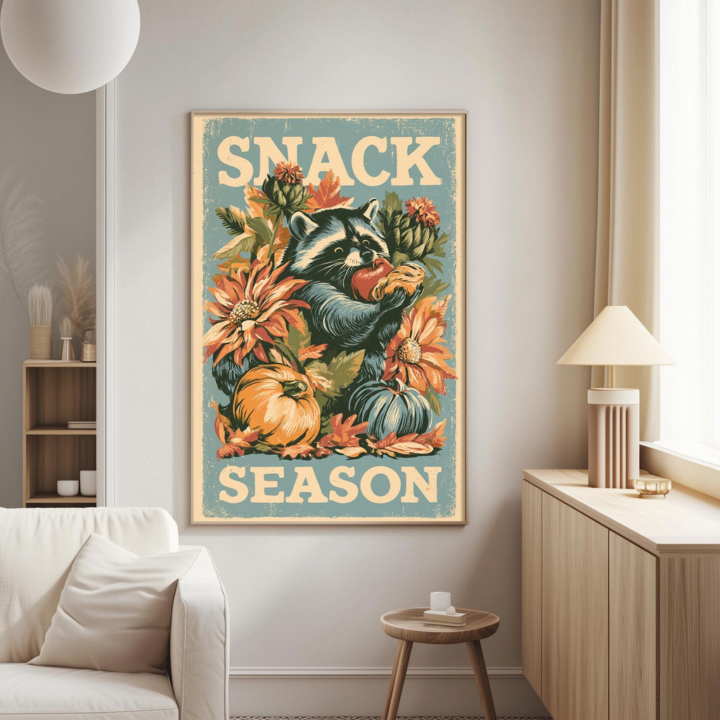 a poster with a raccoon holding a piece of fruit, surrounded by autumn-themed elements such as flowers and pumpkins, with the text "SNACK SEASON" prominently displayed.