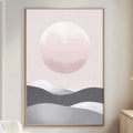 a living room with a large framed poster of a mountain landscape hanging on the wall. The poster has a pink and gray color scheme, and it appears to depict a serene mountain scene with a large moon in the sky. The room also includes a white sofa, a wooden side table, and a lamp on a nearby table.
