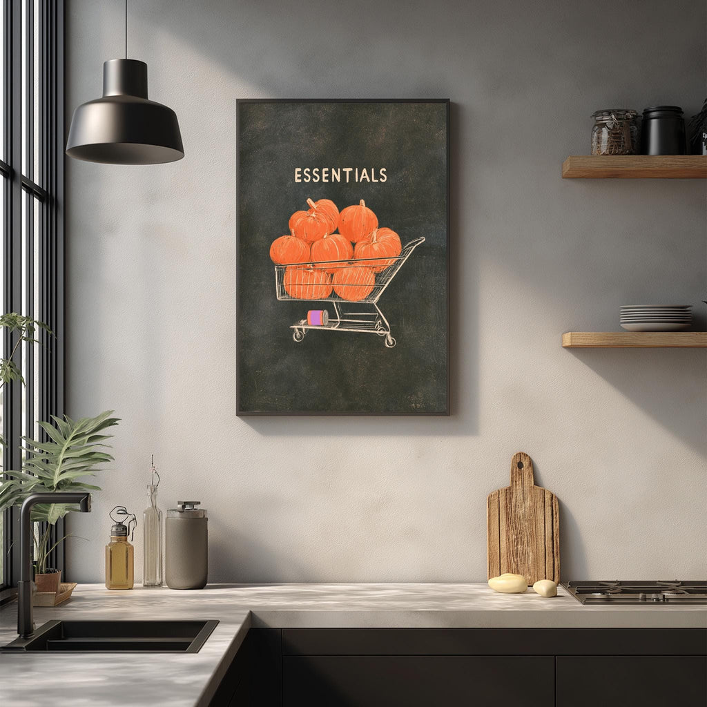 a kitchen counter with various kitchen items, including a wooden cutting board, a sink, and a potted plant. Above the counter, there is a framed illustration of a shopping cart filled with pumpkins, with the text "Essentials" written on it.