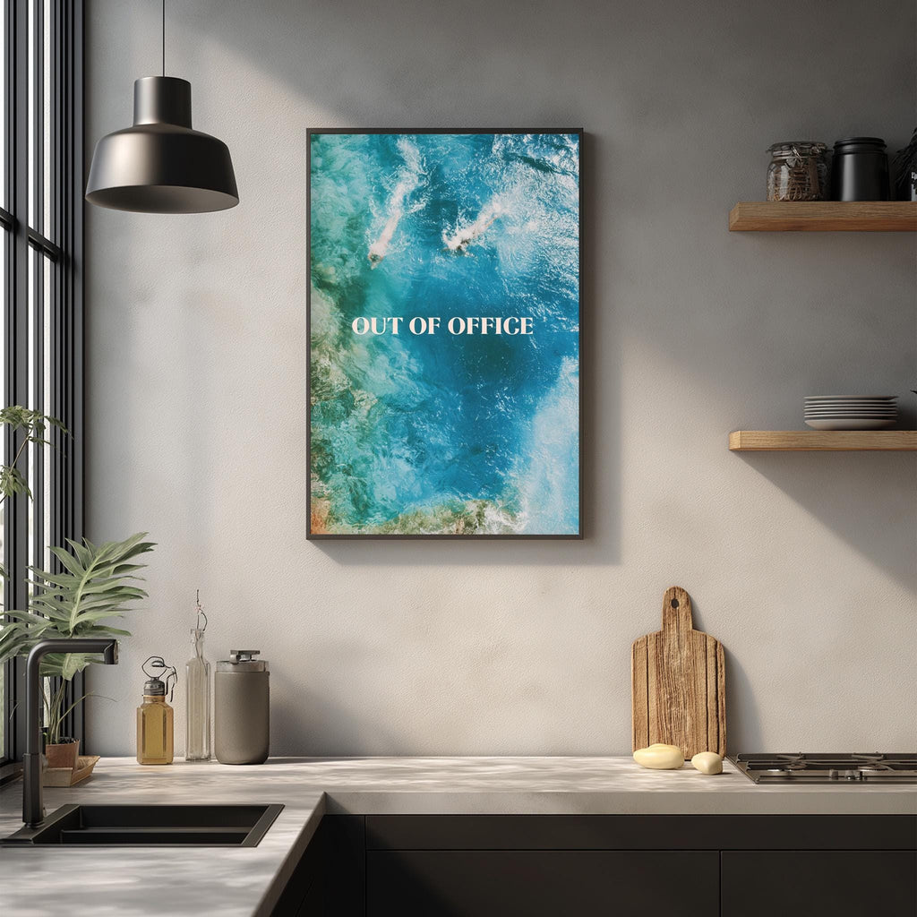 a kitchen counter with various items, including a cutting board, a sink, and a potted plant. Above the counter, there is a framed poster with the text "OUT OF OFFICE" written on it.