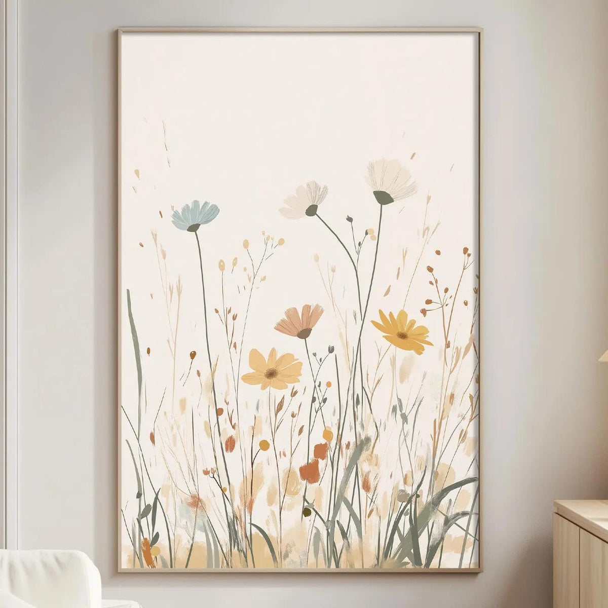 a living room with a large floral print hanging on the wall, featuring a field of flowers in various colors. The room has a white sofa, a wooden side table, and a lamp on a wooden cabinet.