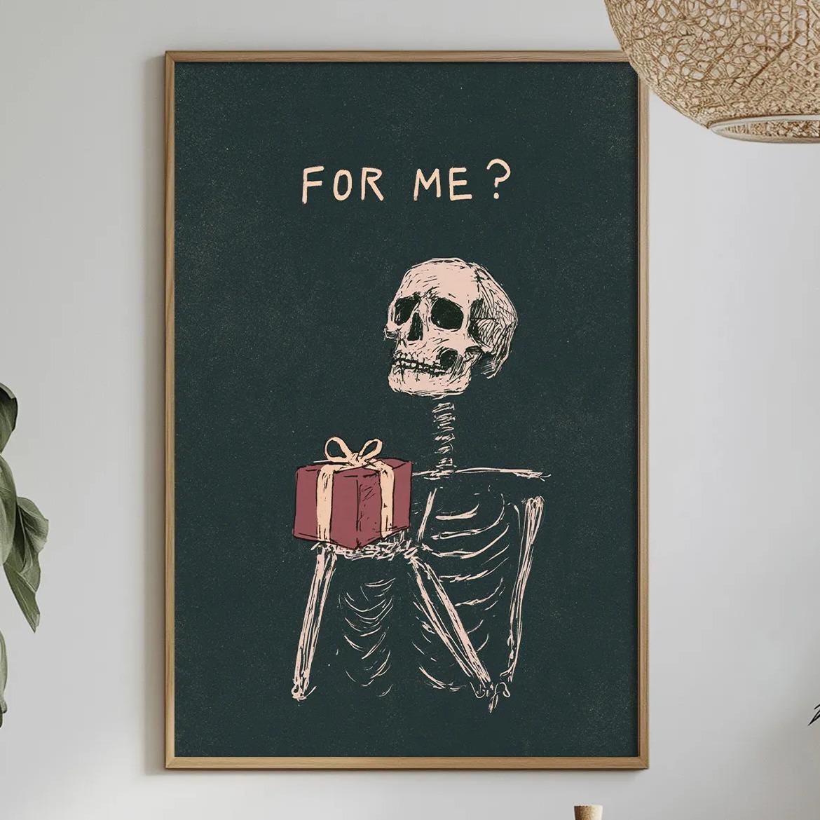a framed illustration of a skeleton holding a gift, with the text "FOR ME?" displayed above it. The scene includes a dining table with a vase of flowers, a potted plant, and a bottle of wine.
