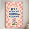 a poster with a checkered pink and white background, a purple flower, and the text "It's a good day to have a good day" written in blue.