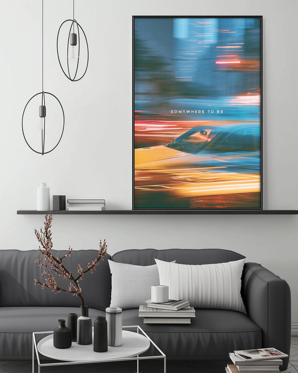 a modern living room with a gray sofa, a coffee table, and a large framed artwork depicting a car in motion. The artwork has a vibrant color palette and the phrase " Somewhere to be" is prominently displayed.