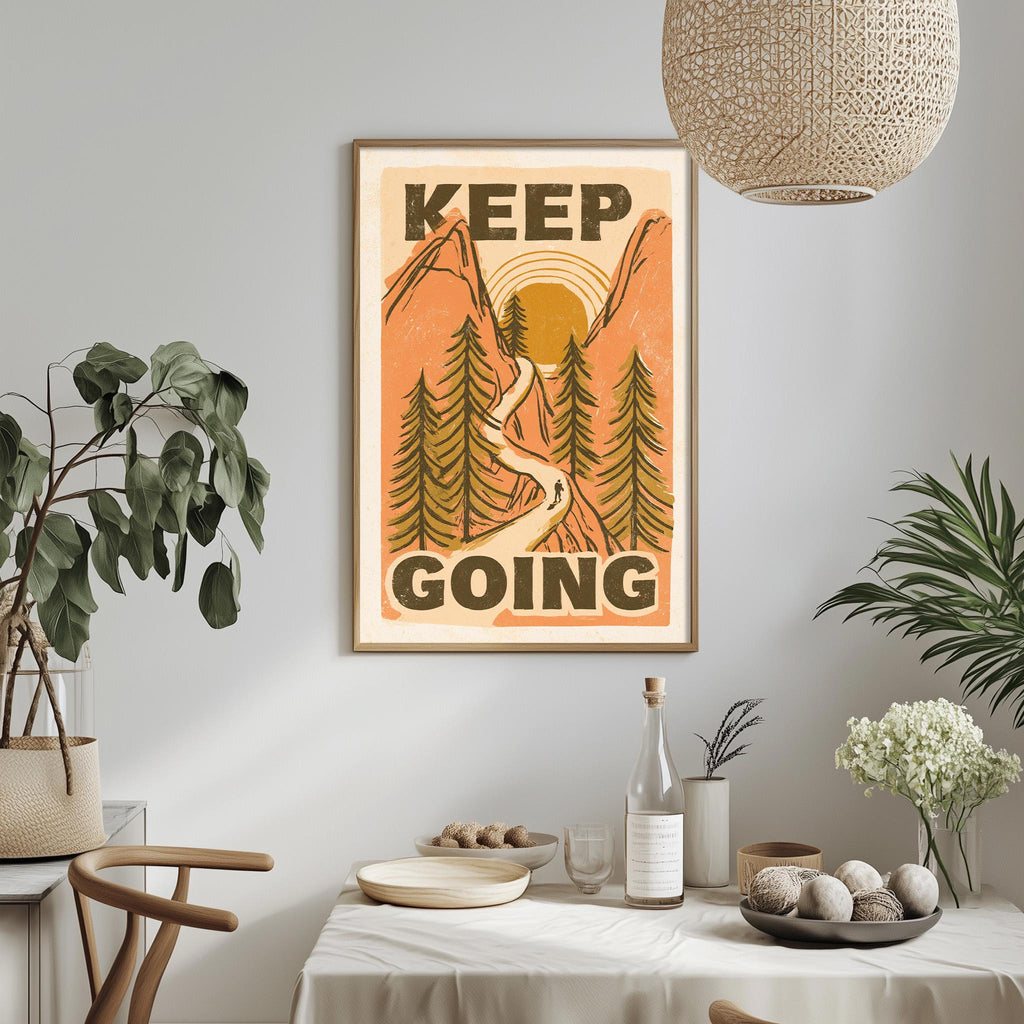 a framed poster with the text "KEEP GOING" hanging on a wall above a dining table with various items on it, including a bottle, a bowl, and a vase.