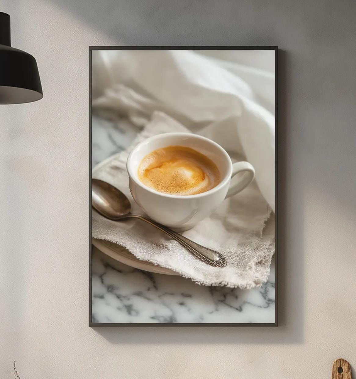 a framed photograph of a cup of coffee on a marble countertop, with a wooden cutting board and other kitchen items visible below the frame.