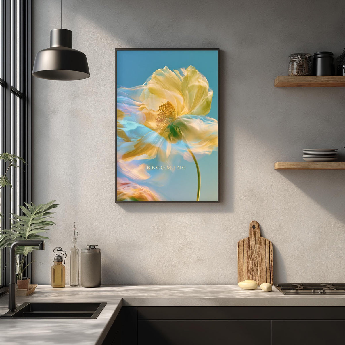 a kitchen counter with various items such as a cutting board, a soap dispenser, and a plant. Above the counter, there is a framed picture of a yellow flower with a blue background, and the word "BECOMING" is written below the flower.