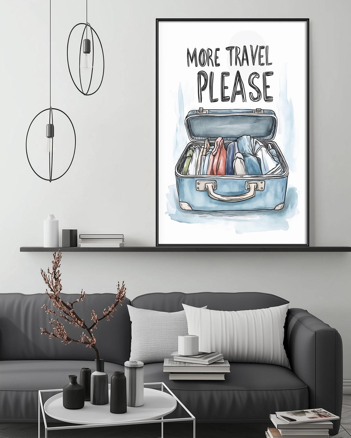a living room with a gray couch, a coffee table, and a framed poster with a suitcase illustration and the text "MORE TRAVEL PLEASE" above it.