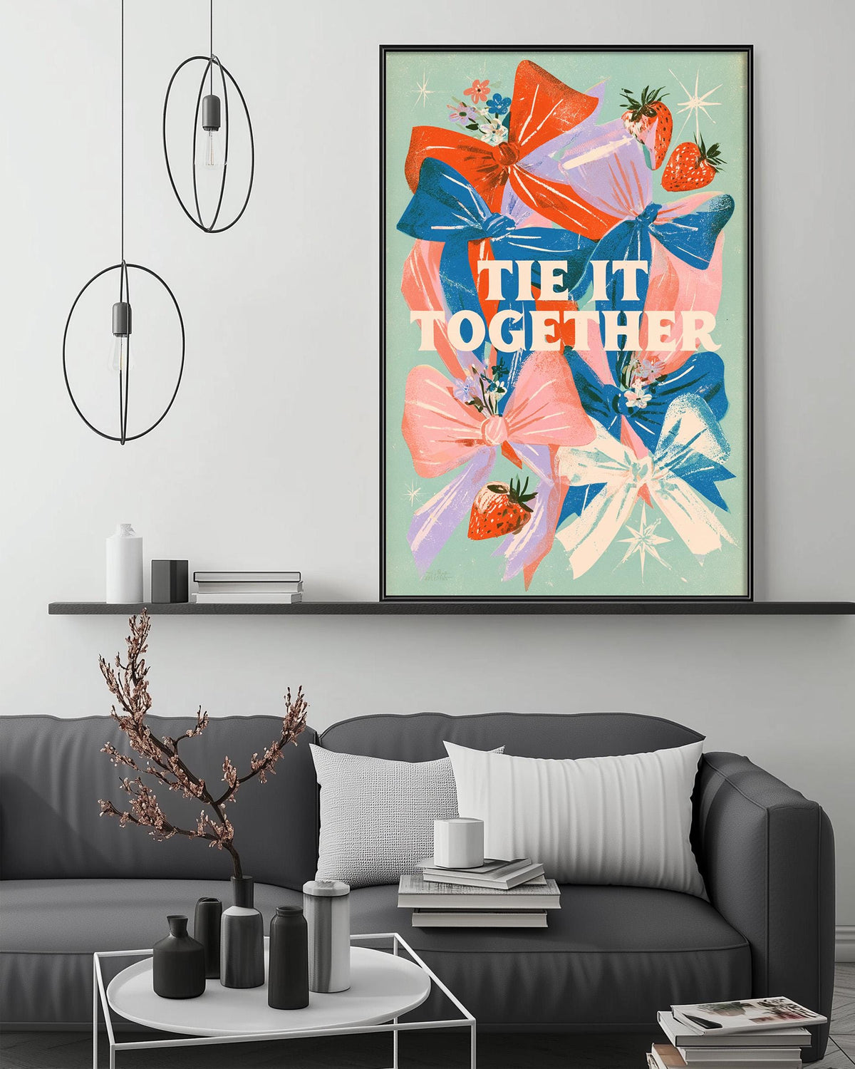 a modern living room with a gray sofa, a coffee table, and a large framed poster with a floral design and the text "tie it together" on the wall.