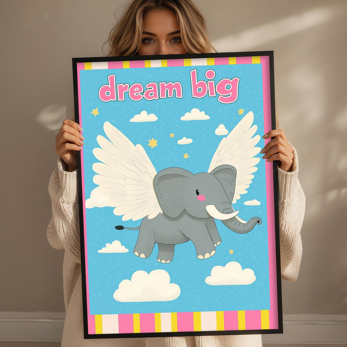A woman is holding up a framed poster with an illustration of a winged elephant against a blue sky with clouds.