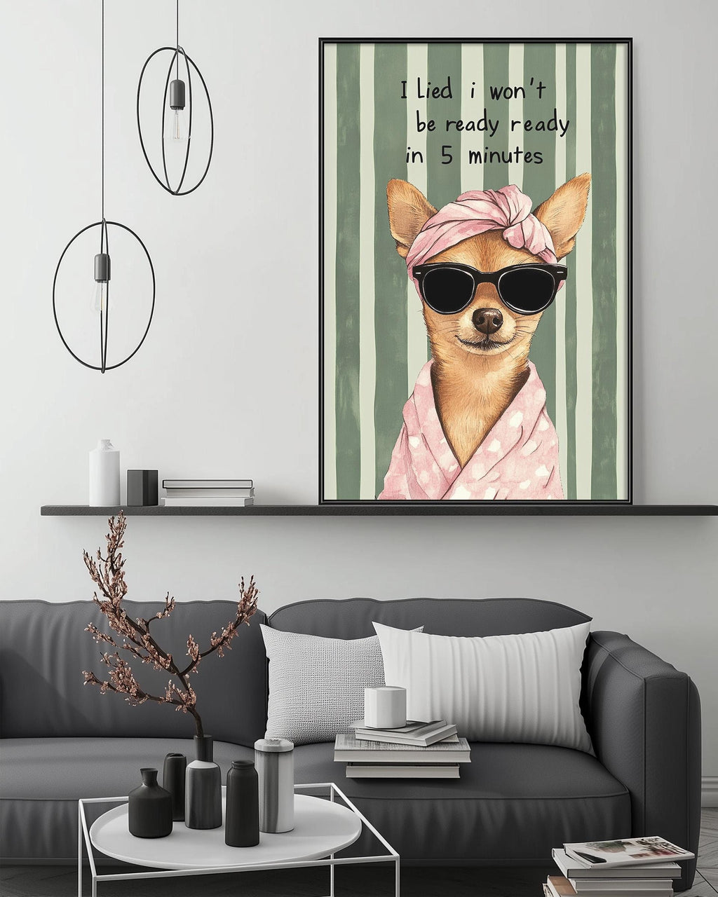 a cozy living room with a gray couch, a coffee table, and a framed poster of a chihuahua wearing sunglasses and a pink scarf. The poster has a humorous caption that reads "I lie, I won't be ready in 5 minutes".