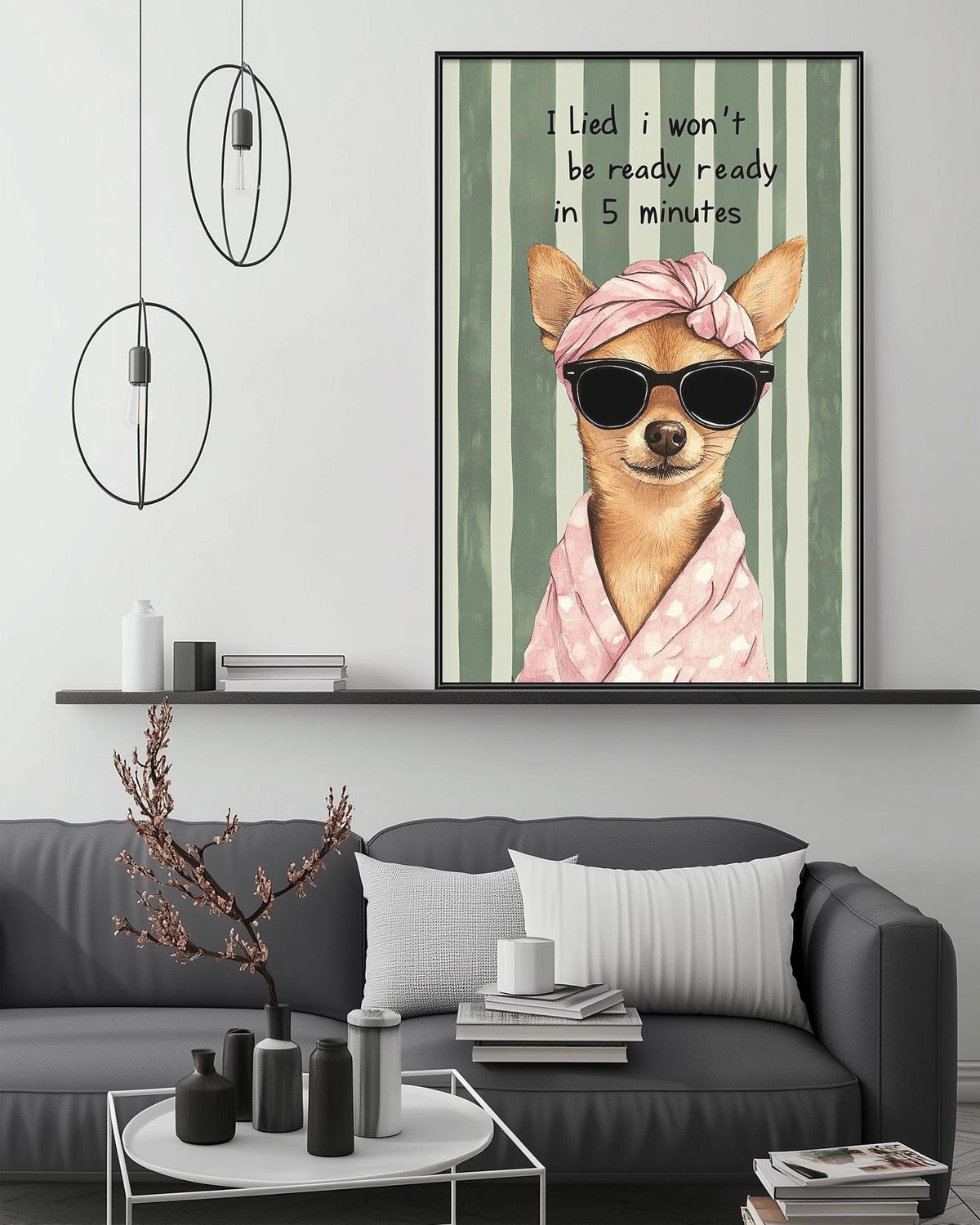 a cozy living room with a gray couch, a coffee table, and a framed poster of a chihuahua wearing sunglasses and a pink scarf. The poster has a humorous caption that reads "I lie, I won't be ready in 5 minutes".