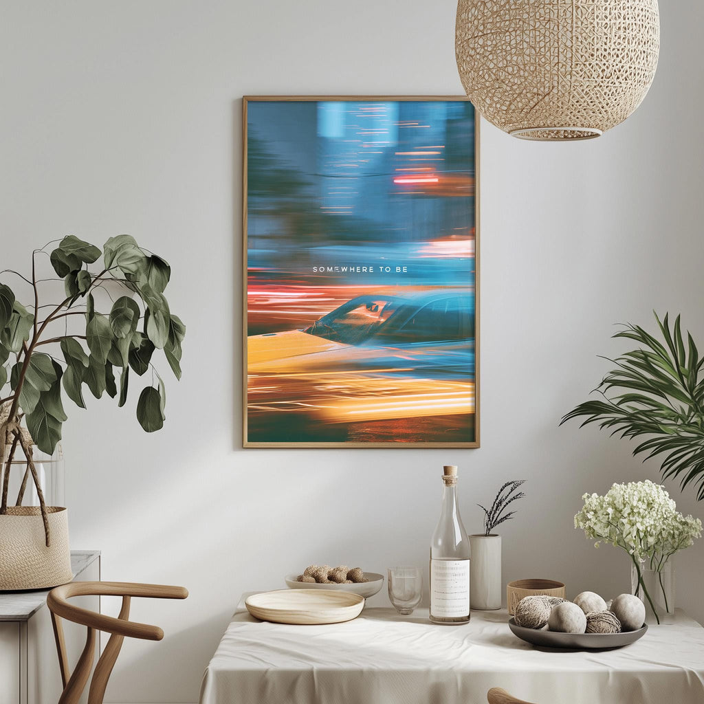 a dining table with a white tablecloth, a bottle, a bowl, and a vase with flowers. Above the table, there is a framed poster with a colorful abstract design. The table is set with various items, including a potted plant, a plant in a vase, and a bowl of fruit.