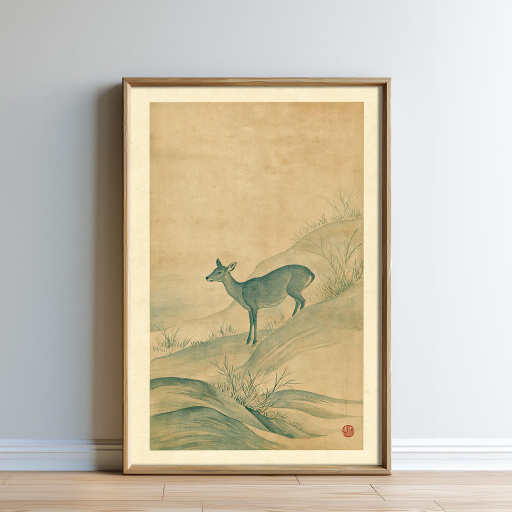 The image is a framed painting depicting a deer standing on a hillside with grass and rocks.