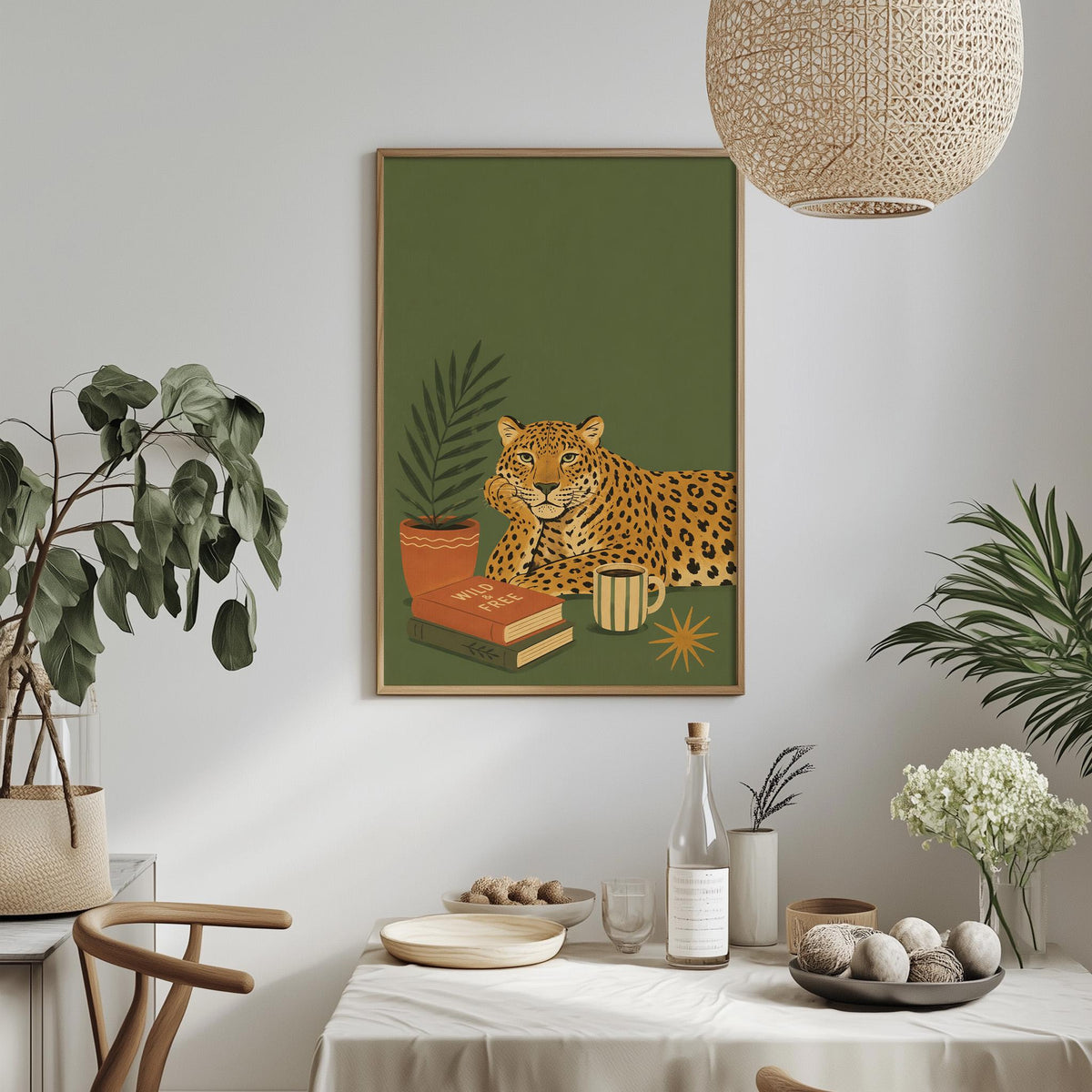 a dining table with a white tablecloth, a bowl of fruit, a bottle, a vase with flowers, and a framed illustration of a leopard resting on a book.