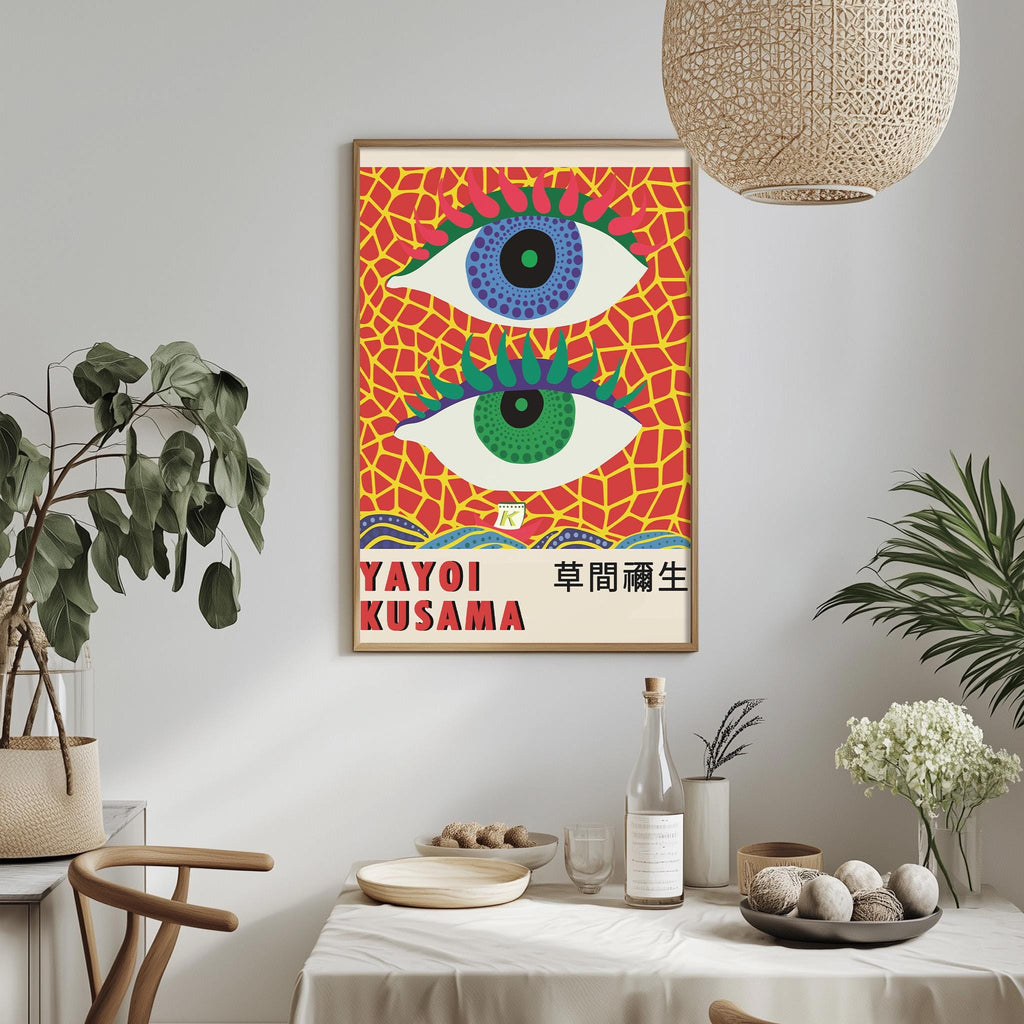 a vibrant poster of Yayoi Kusama's artwork, which includes a striking eye design with a red and yellow background and a white eye surrounded by green and yellow accents. The poster is hung on a wall above a dining table, which is set with various items such as a bottle, a bowl, and a vase. The table also has a potted plant and a bowl of fruit, adding to the overall aesthetic of the scene.