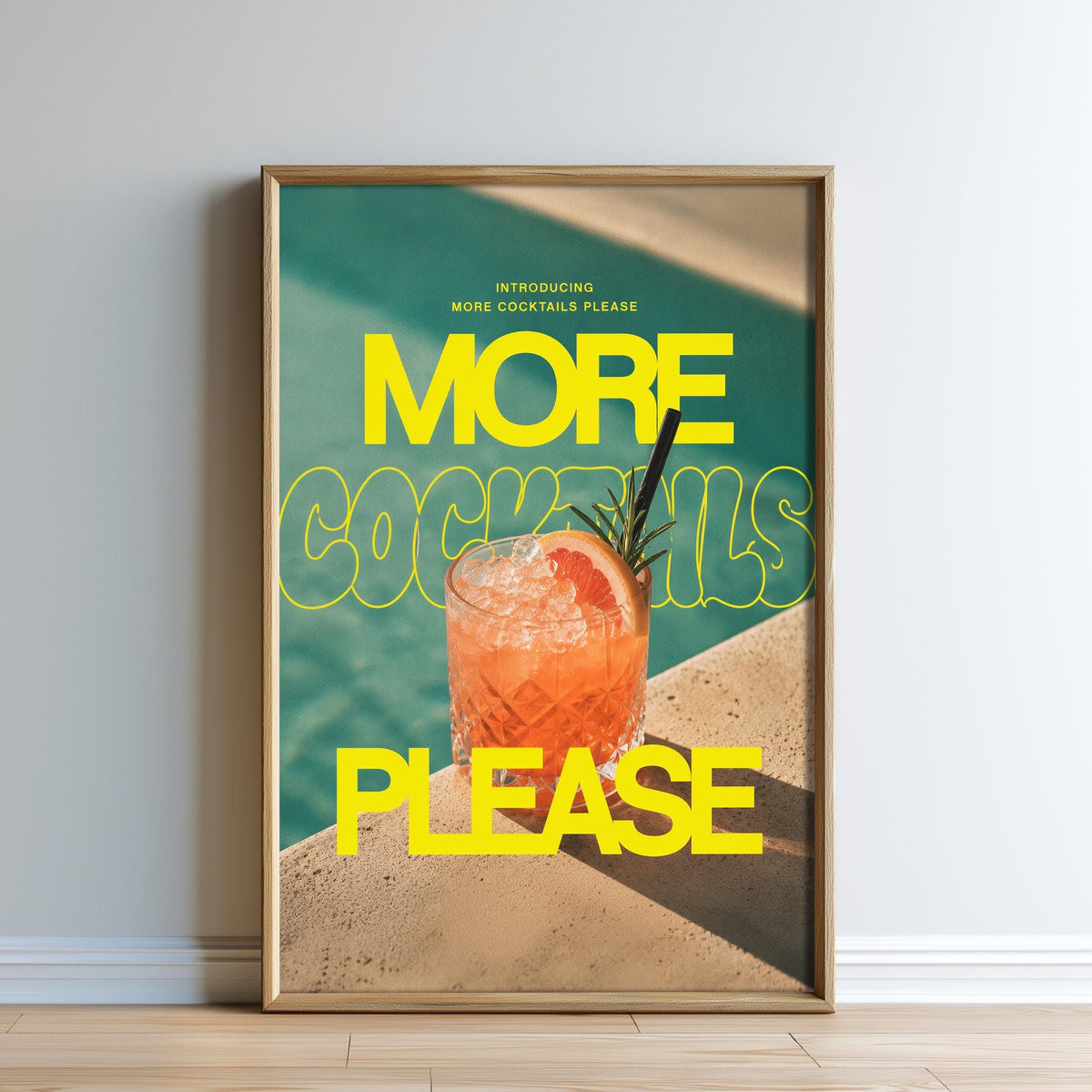 The image is a framed poster with a large text that says "MORE COCKTAILS PLEASE" and a picture of a cocktail on a table.