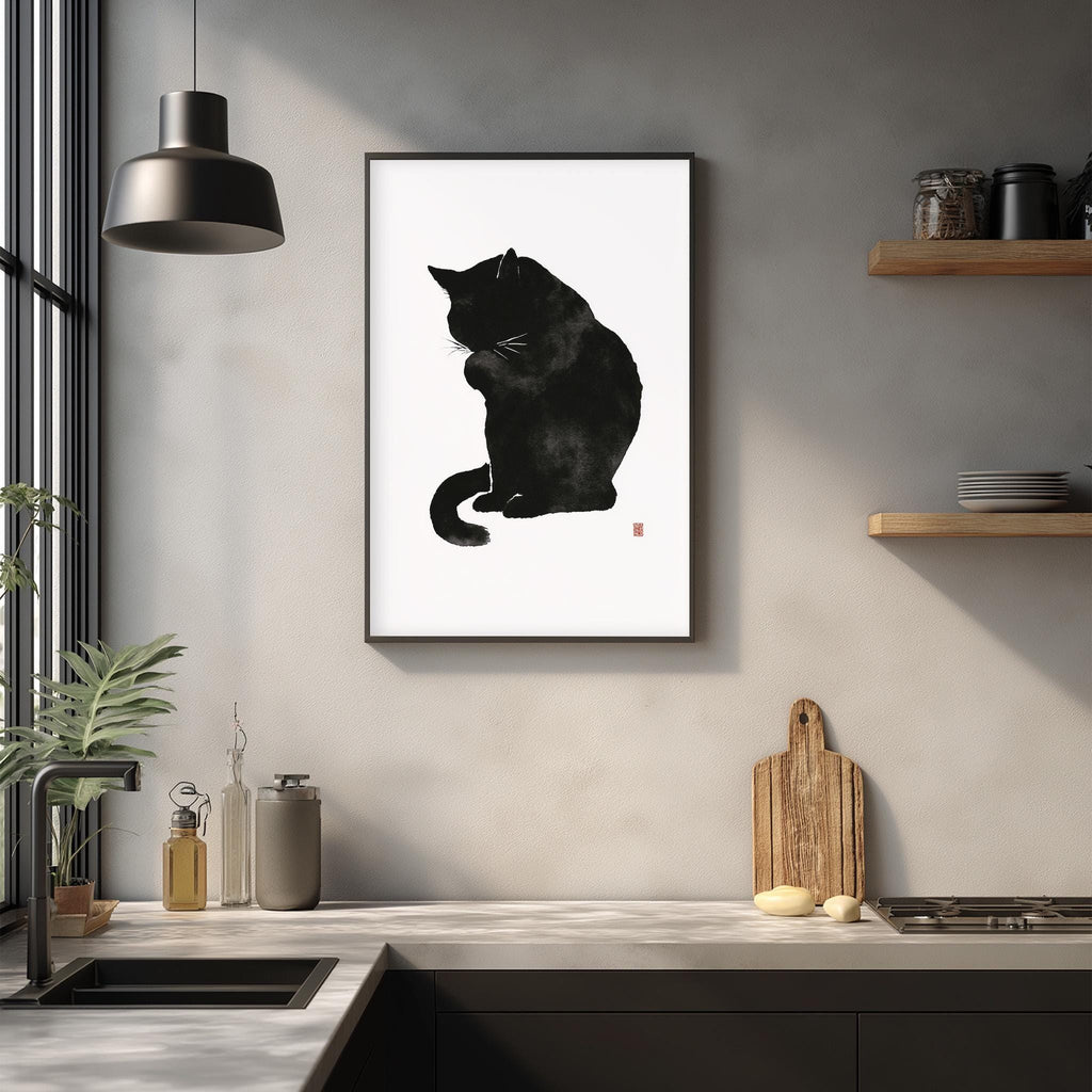 a black cat sitting on a white surface, such as a countertop or table, with a framed picture of the cat hanging on the wall above it.