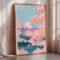 A framed poster of Tokyo, featuring a cityscape with cherry blossoms and a mountain in the background.