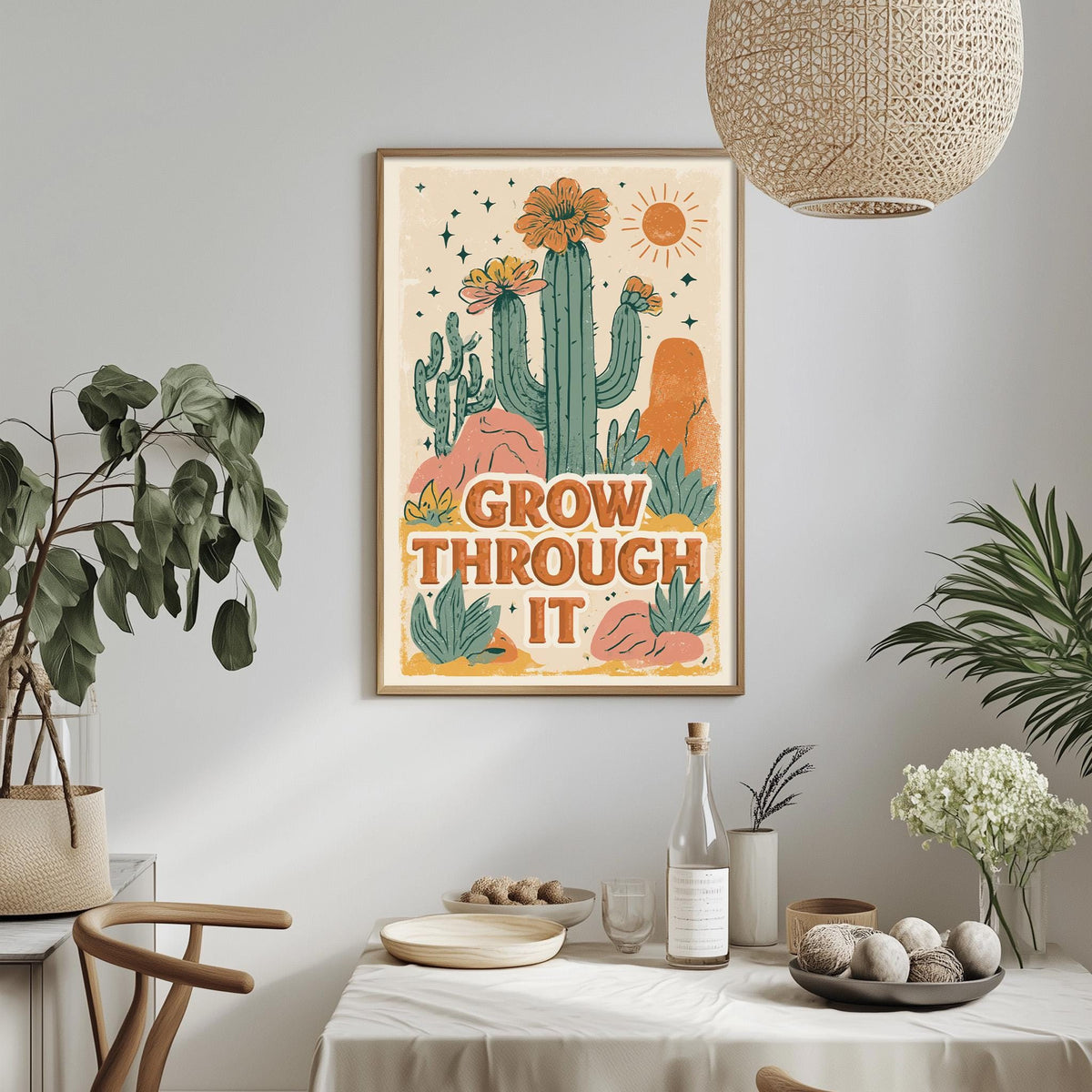 a framed poster with a desert-themed illustration, hanging on a wall above a dining table with various decorative items and plants.
