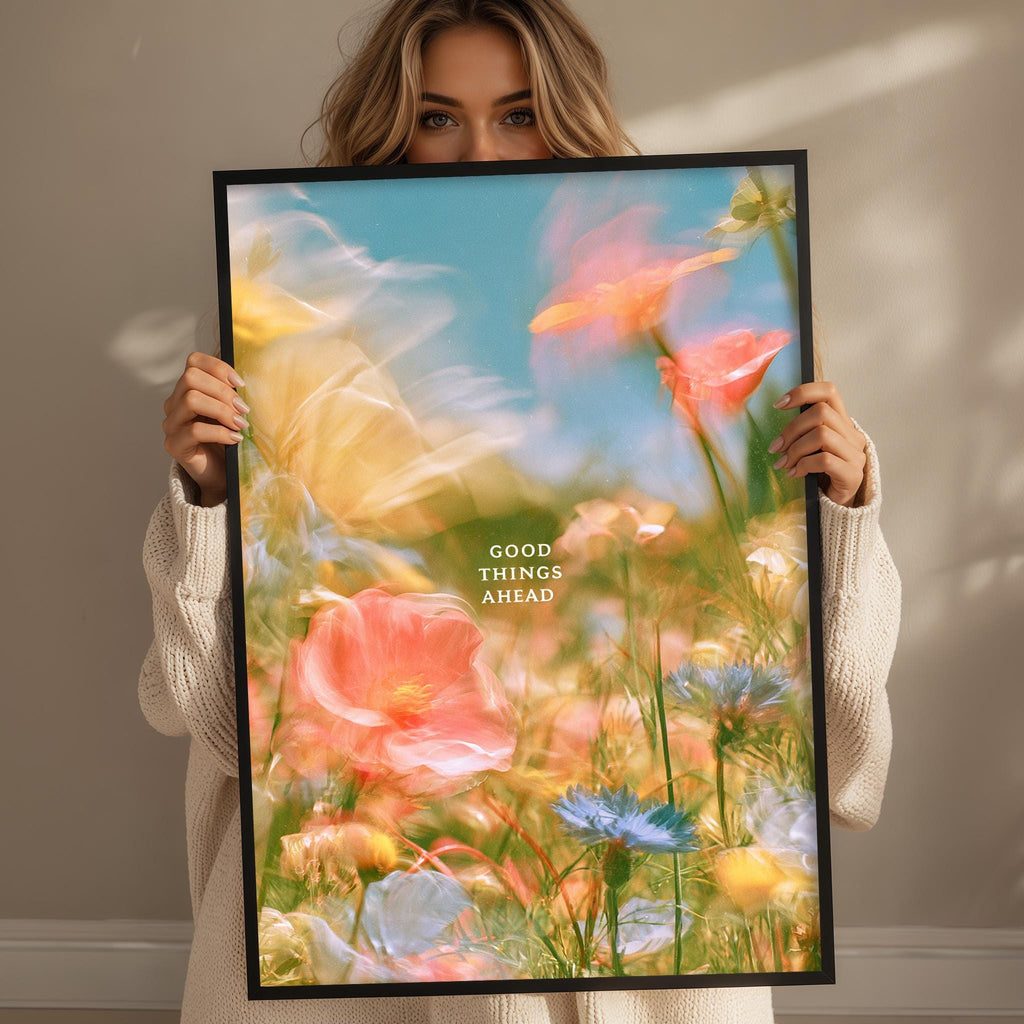 A woman holds up a framed poster with a vibrant, colorful floral scene.