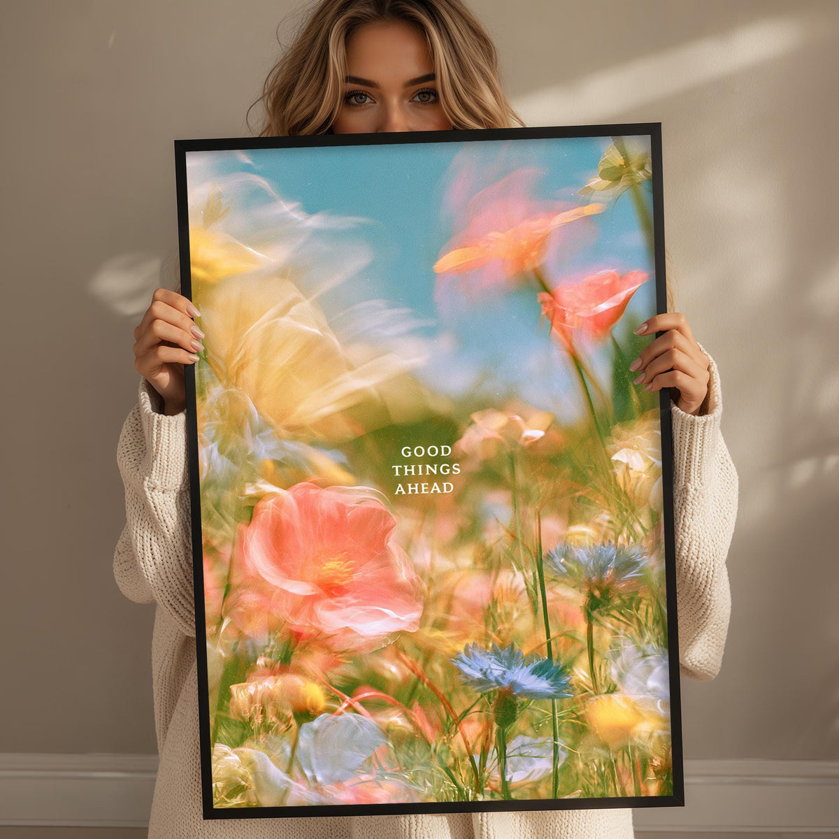 A woman holds up a framed poster with a vibrant, colorful floral scene.