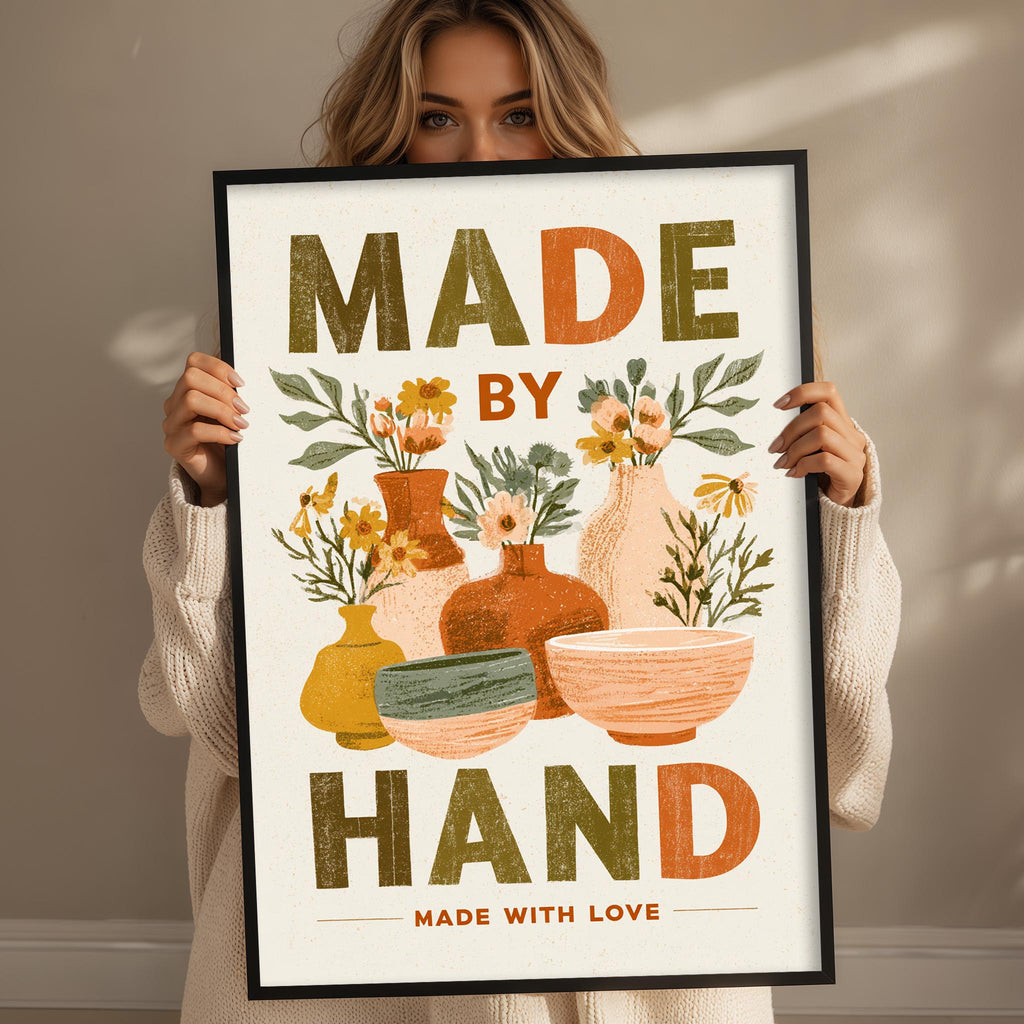 A woman holding a framed poster with the text "MADE BY HAND MADE WITH LOVE" and illustrations of various pottery items.