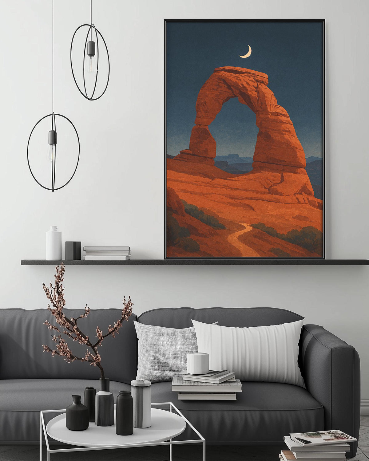a large framed painting of a desert landscape with a crescent moon in the sky, hanging on a wall above a gray couch with white pillows.