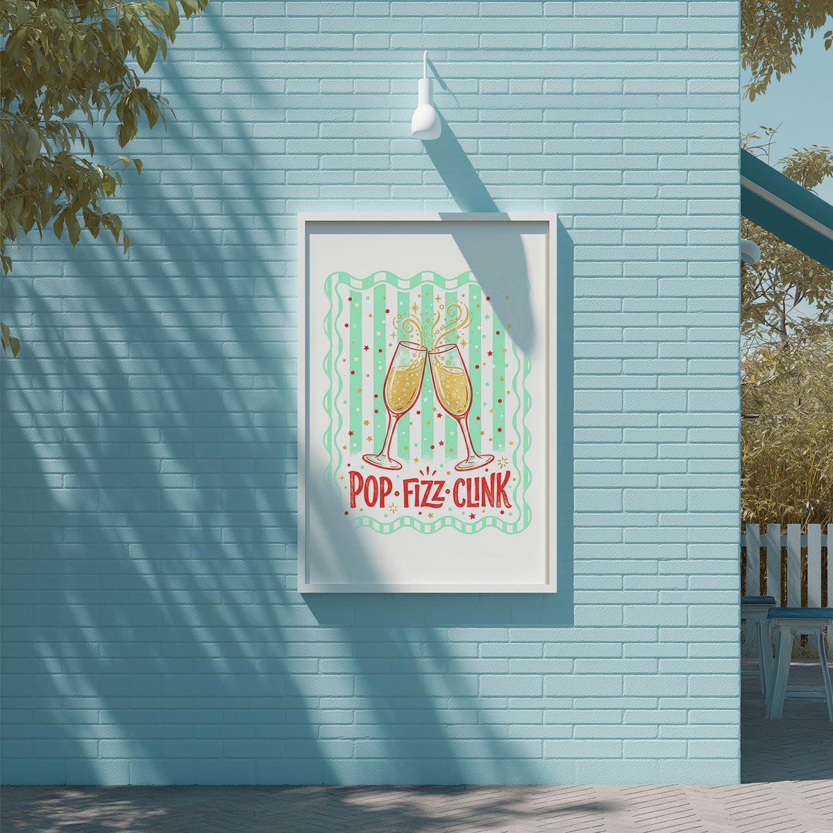 A framed poster with a graphic of two champagne glasses and the text "POP-FIZZ-CLINK" is displayed on a blue brick wall.