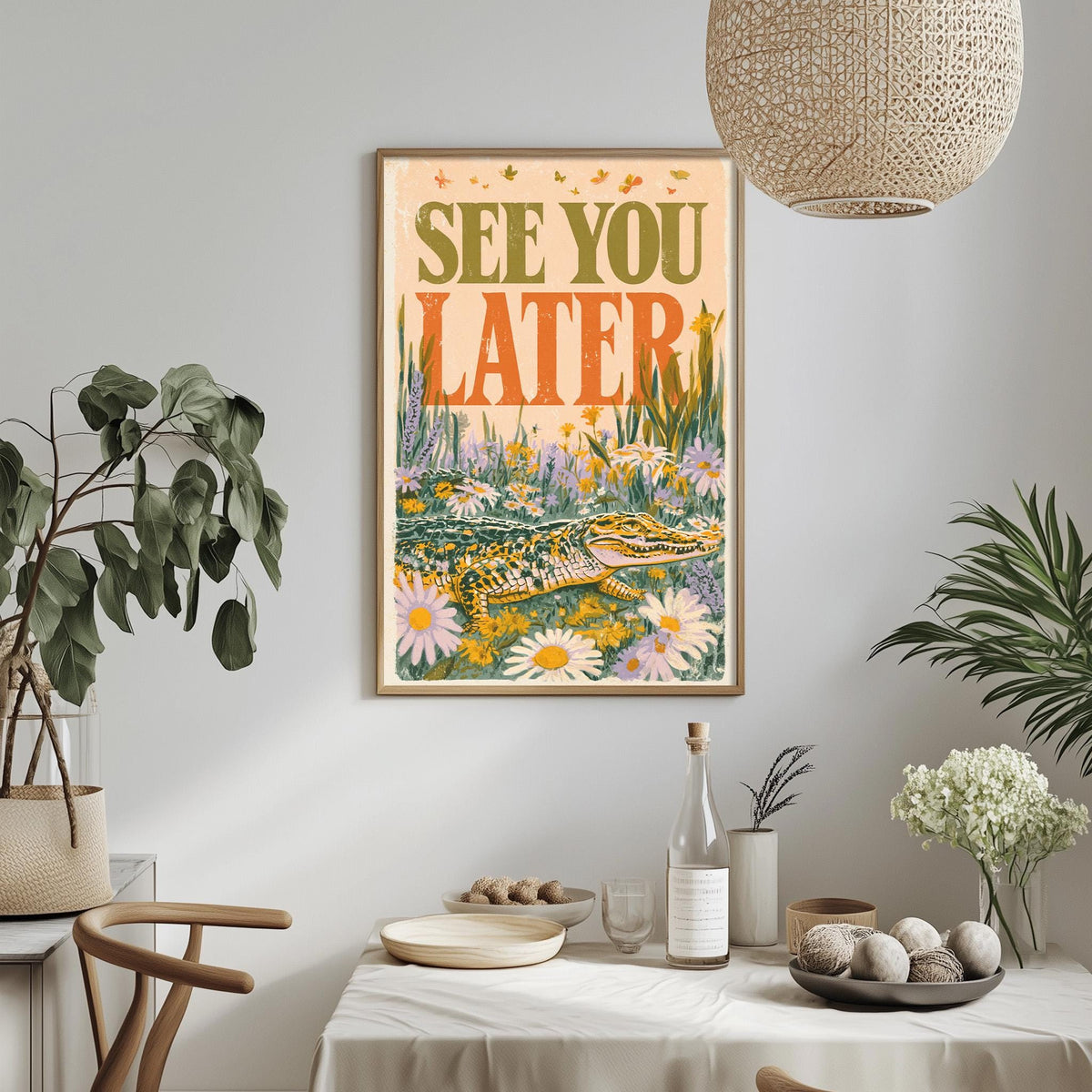a framed poster with a vibrant illustration of a crocodile surrounded by flowers, hanging on a wall above a dining table with various decorative items and plants.