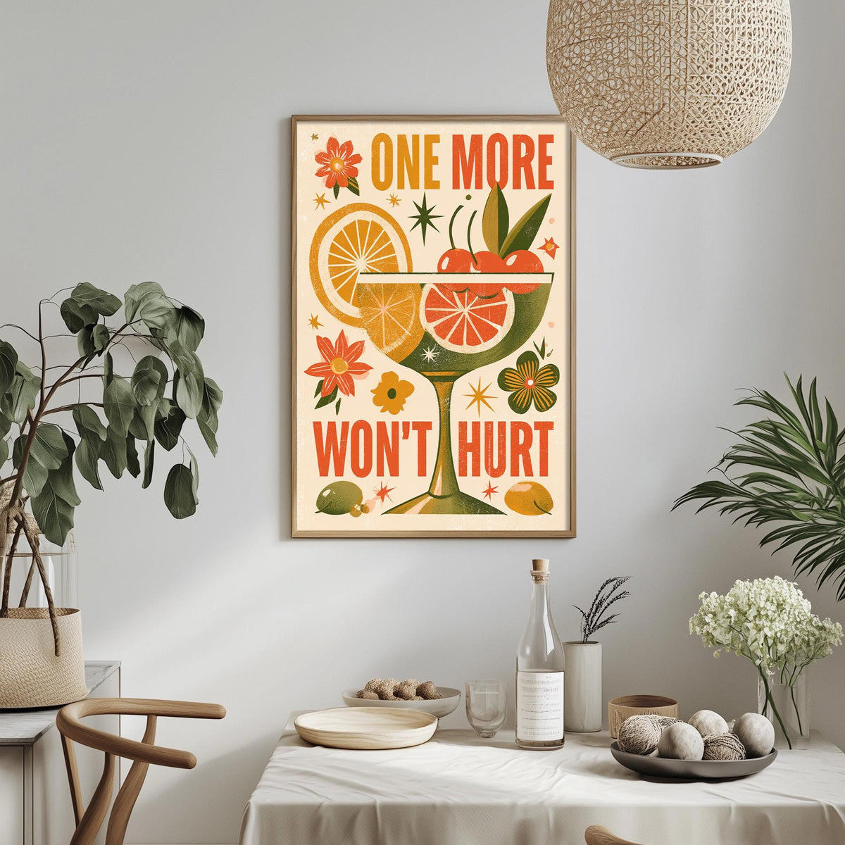 a framed poster with a vibrant design of a cocktail glass, citrus fruits, and flowers, hanging on a wall above a dining table.