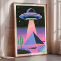 a large framed poster depicting an alien spacecraft hovering over a desert landscape with a cactus and pyramid in the background.