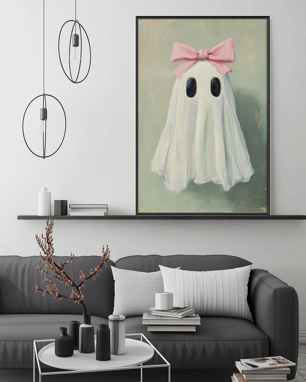 a living room with a gray couch, a coffee table, and a large framed painting of a ghost with a pink bow on its head. The painting is hanging on the wall above the couch.