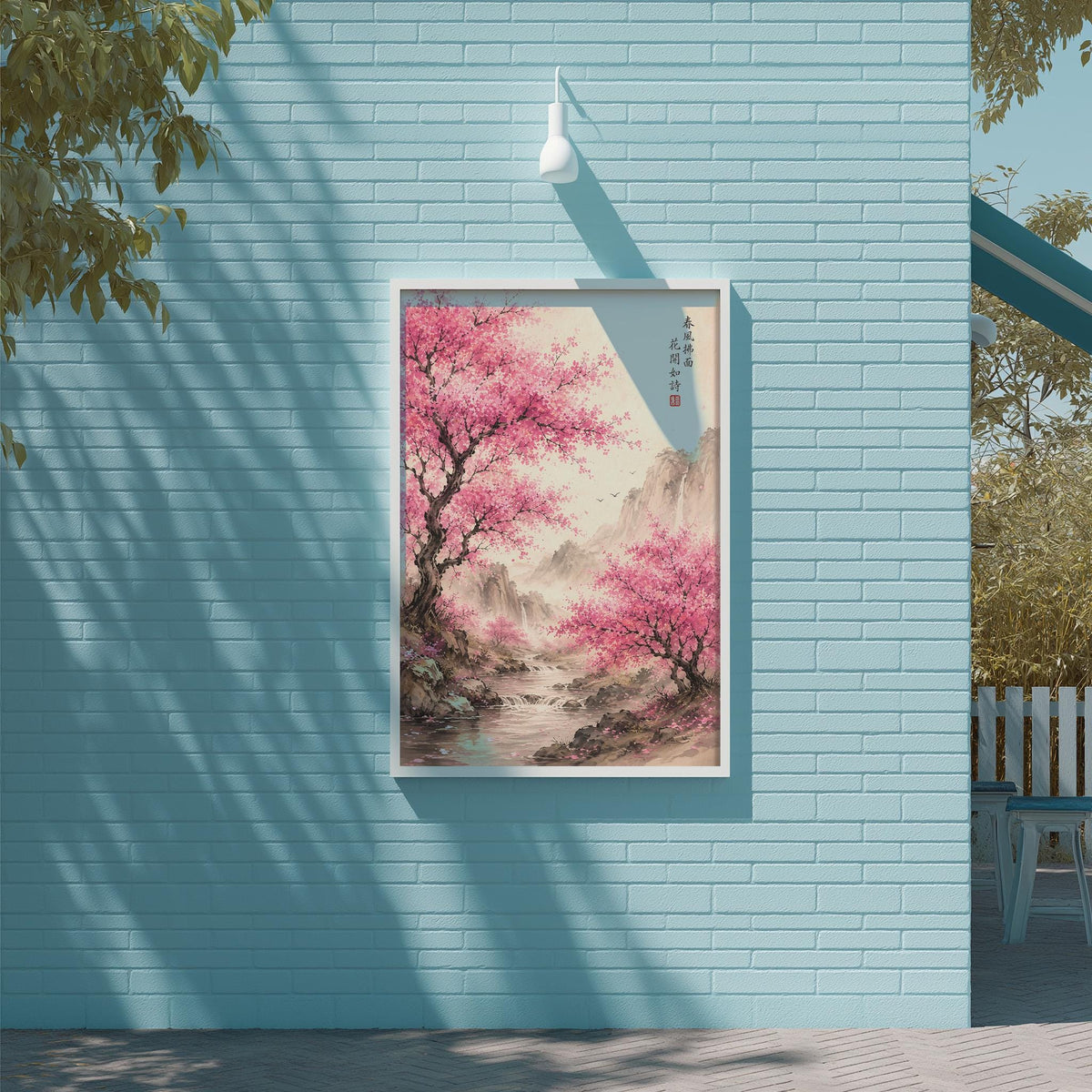 a blue brick wall with a framed painting of a pink tree and a mountain landscape hanging on it.