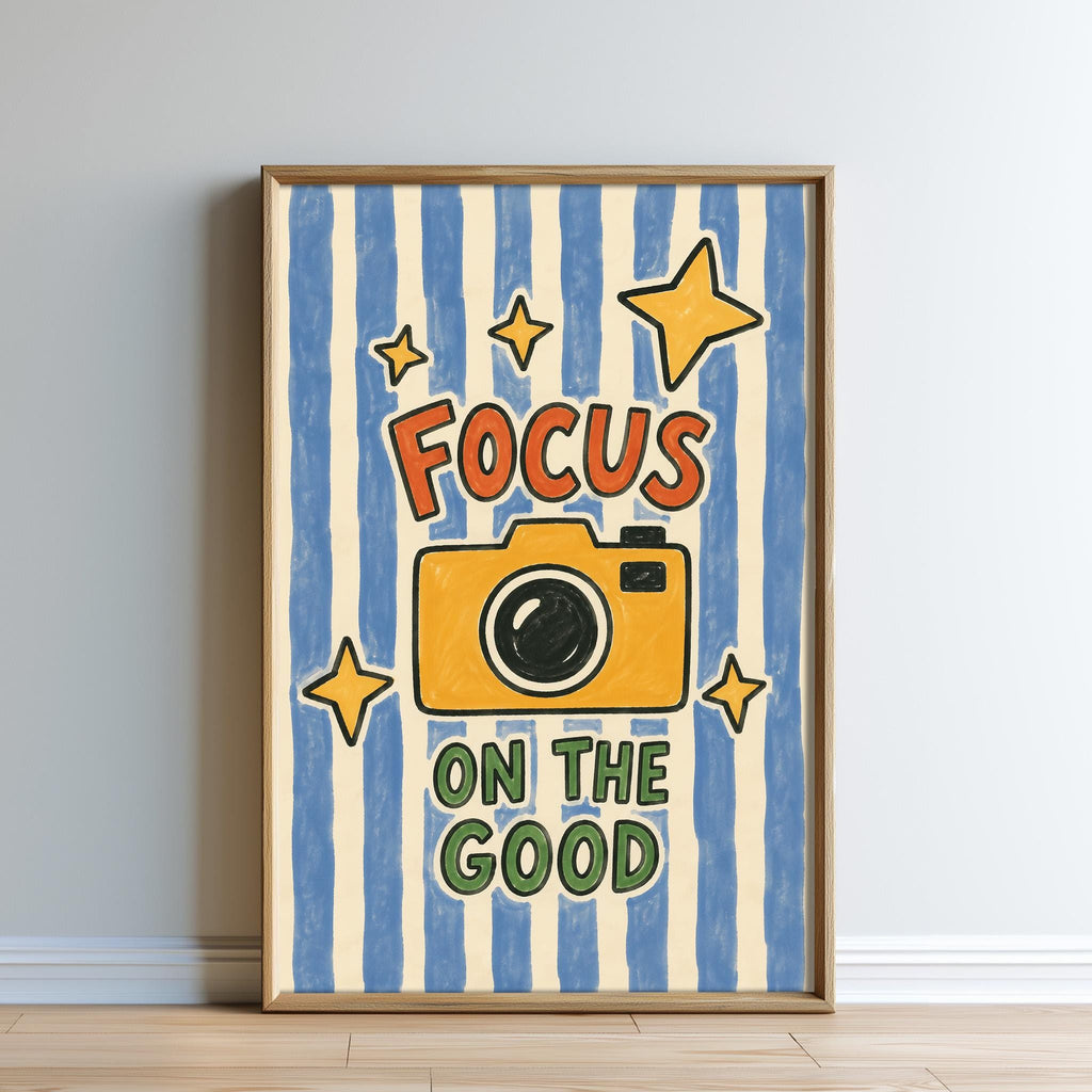 The image is a framed poster with a yellow camera and the text "Focus on the good" written on it.