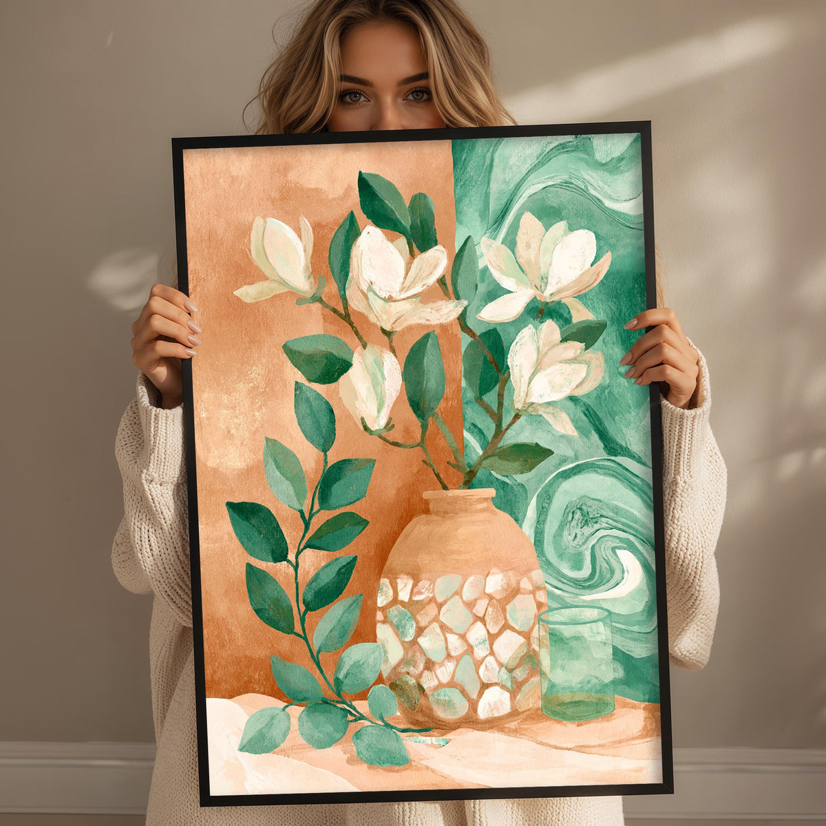 A woman holds up a framed painting of a vase with flowers and leaves against a background of green and orange hues.